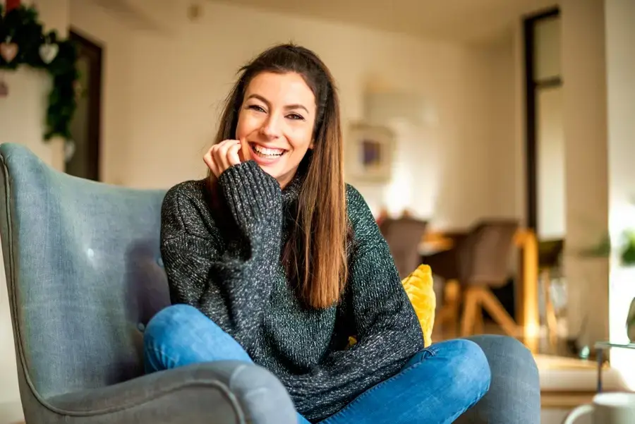 smiling woman sitting on a couch in a sober living recovery home