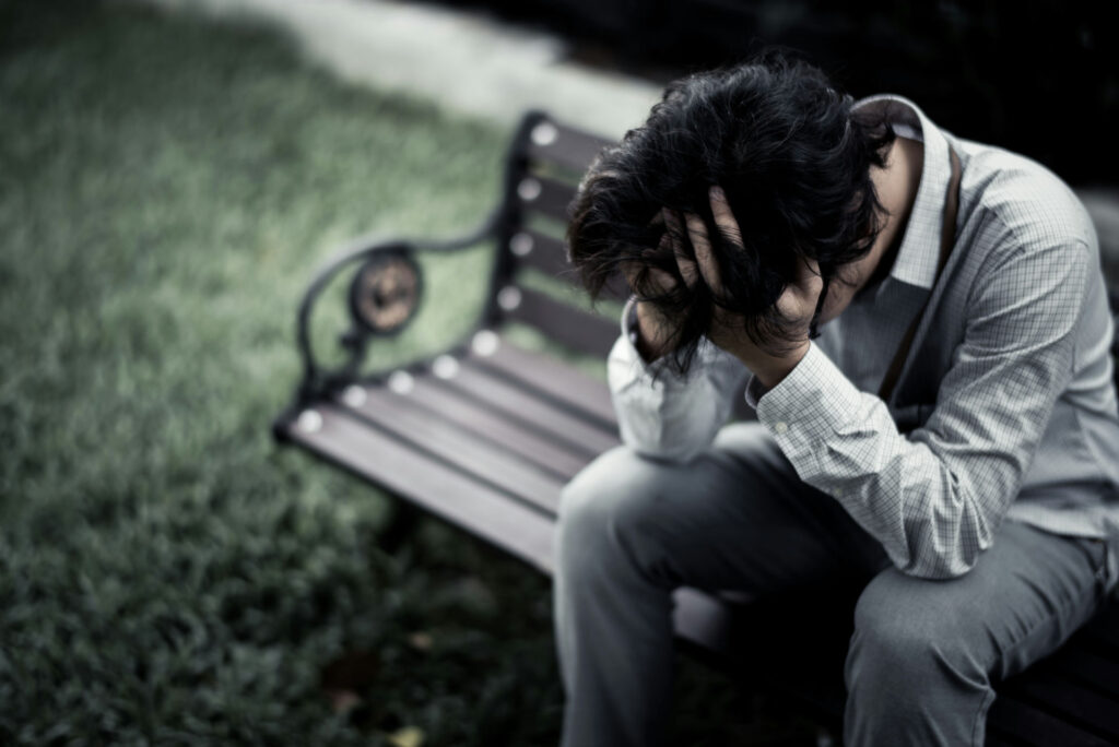 Person sitting alone outdoors struggling with Gas Station Heroin addiction and withdrawal